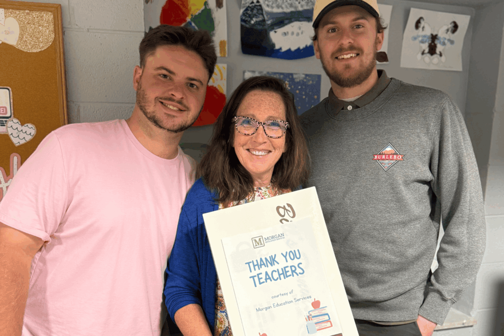 A female teacher being recognized for her work alongside two others