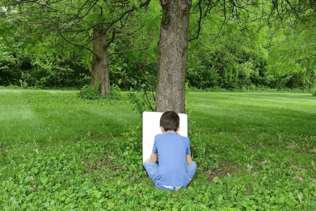 Kid drawing under a tree